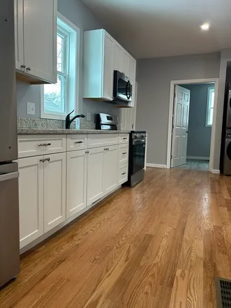 a kitchen with granite countertop a sink cabinets and wooden floor