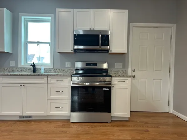 a kitchen with stainless steel appliances granite countertop a stove a microwave and a white cabinets