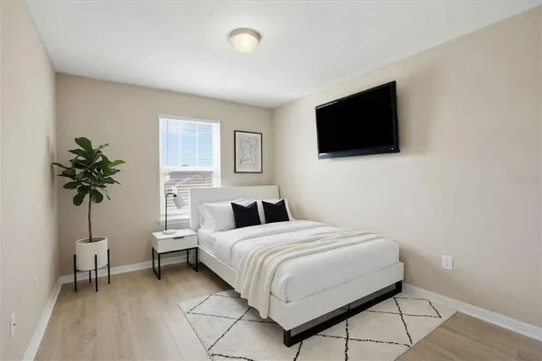 a bedroom with a bed a flat screen tv and a potted plant