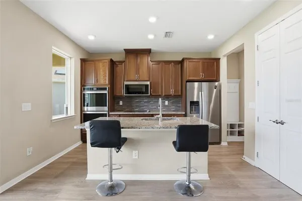 a kitchen with stainless steel appliances kitchen island granite countertop a refrigerator a stove a sink dishwasher with a dining table and chair