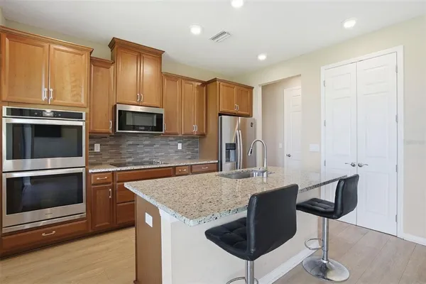 a kitchen with stainless steel appliances granite countertop a refrigerator a stove a sink and a microwave