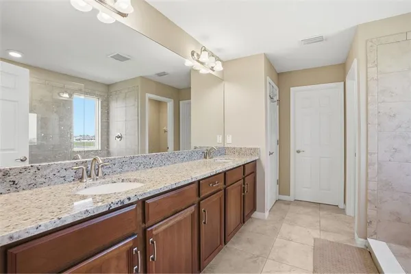 a bathroom with a granite countertop sink a large mirror and a shower