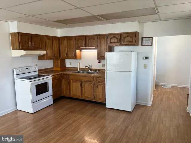 a kitchen with a refrigerator a stove top oven a sink and dishwasher with wooden floor