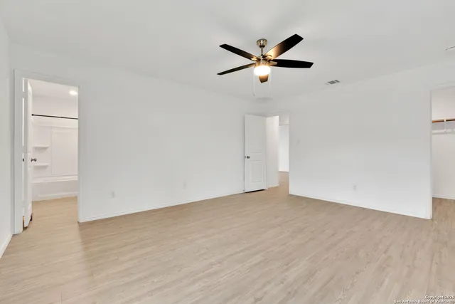 an empty room with wooden floor closet and windows