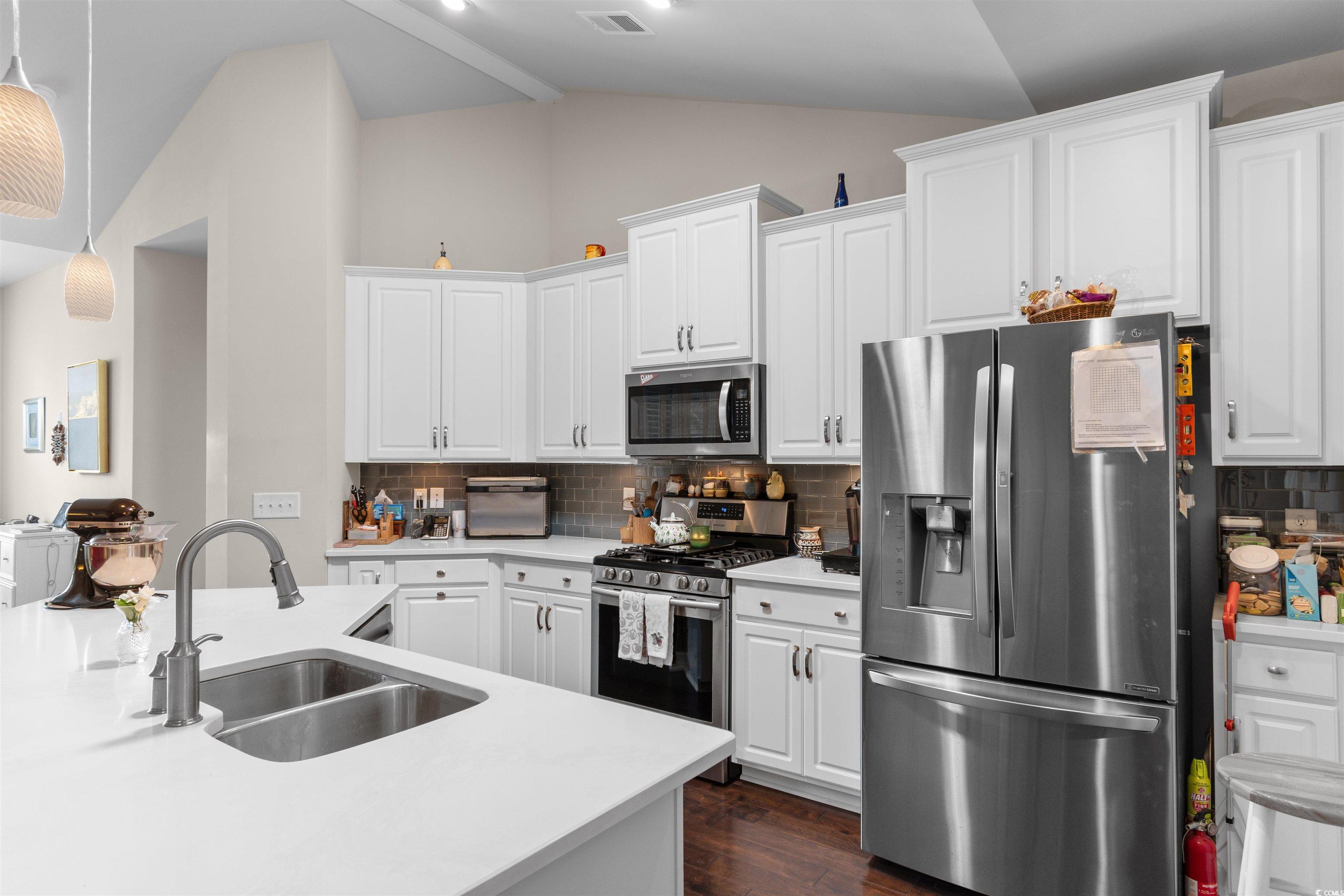 765 Berkshire Avenue Myrtle Beach, SC 29577 - Photo 6 of 40 Kitchen with appliances with stainless steel finishes, a sink, vaulted ceiling, decorative backsplash, and dark wood-style floors