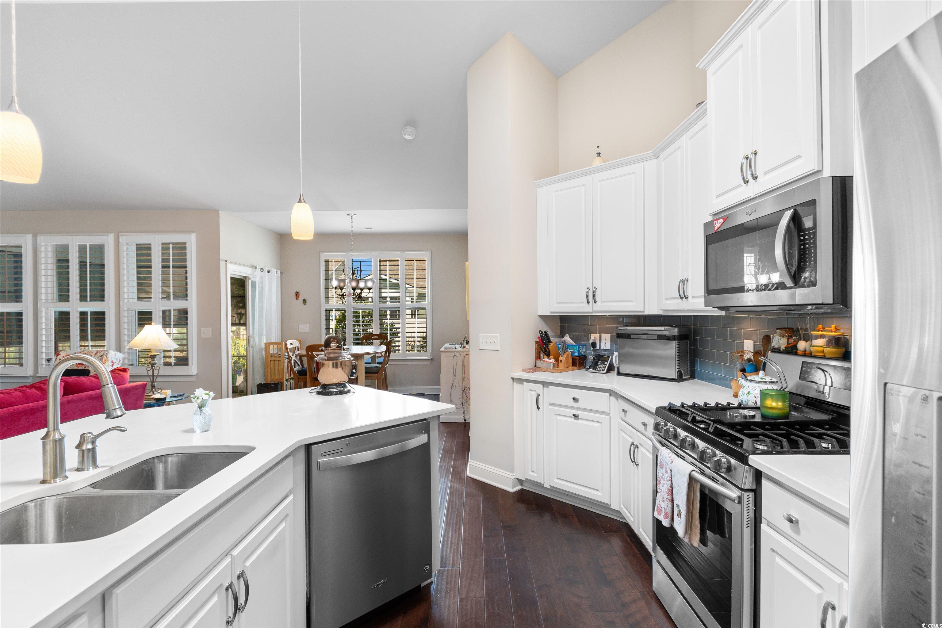 765 Berkshire Avenue Myrtle Beach, SC 29577 - Photo 7 of 40 Kitchen featuring stainless steel appliances, a sink, dark wood finished floors, light countertops, and backsplash