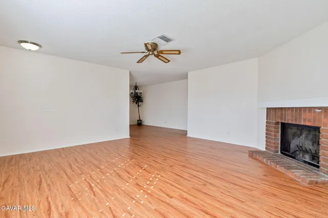 a view of empty room with wooden floor and fireplace