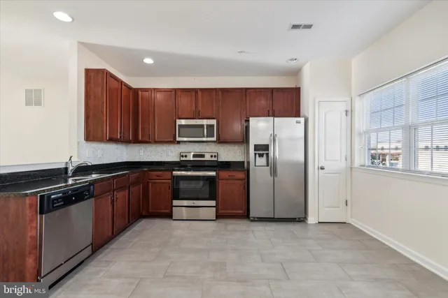 a kitchen with stainless steel appliances granite countertop a refrigerator and a stove top oven