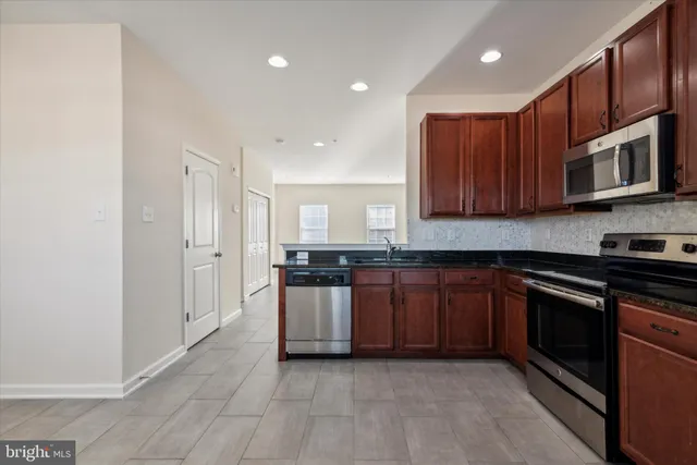 a kitchen with stainless steel appliances granite countertop a stove a sink and a microwave