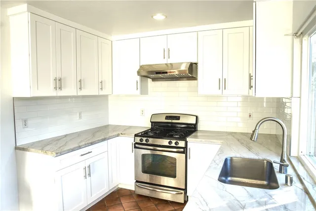 a kitchen with granite countertop a stove a sink and a microwave