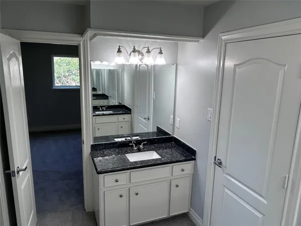 a bathroom with a granite countertop sink and a mirror