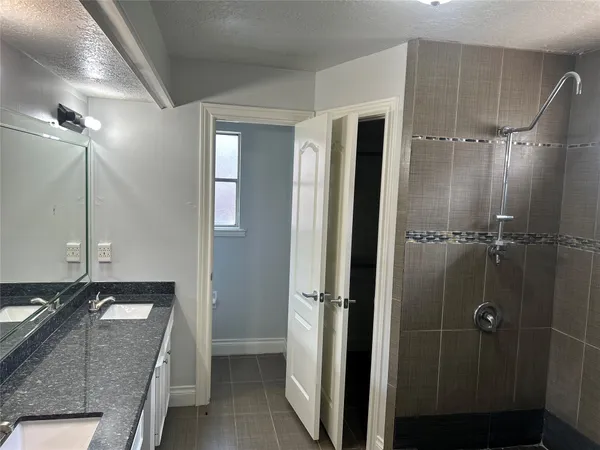 a bathroom with a granite countertop sink a mirror and shower