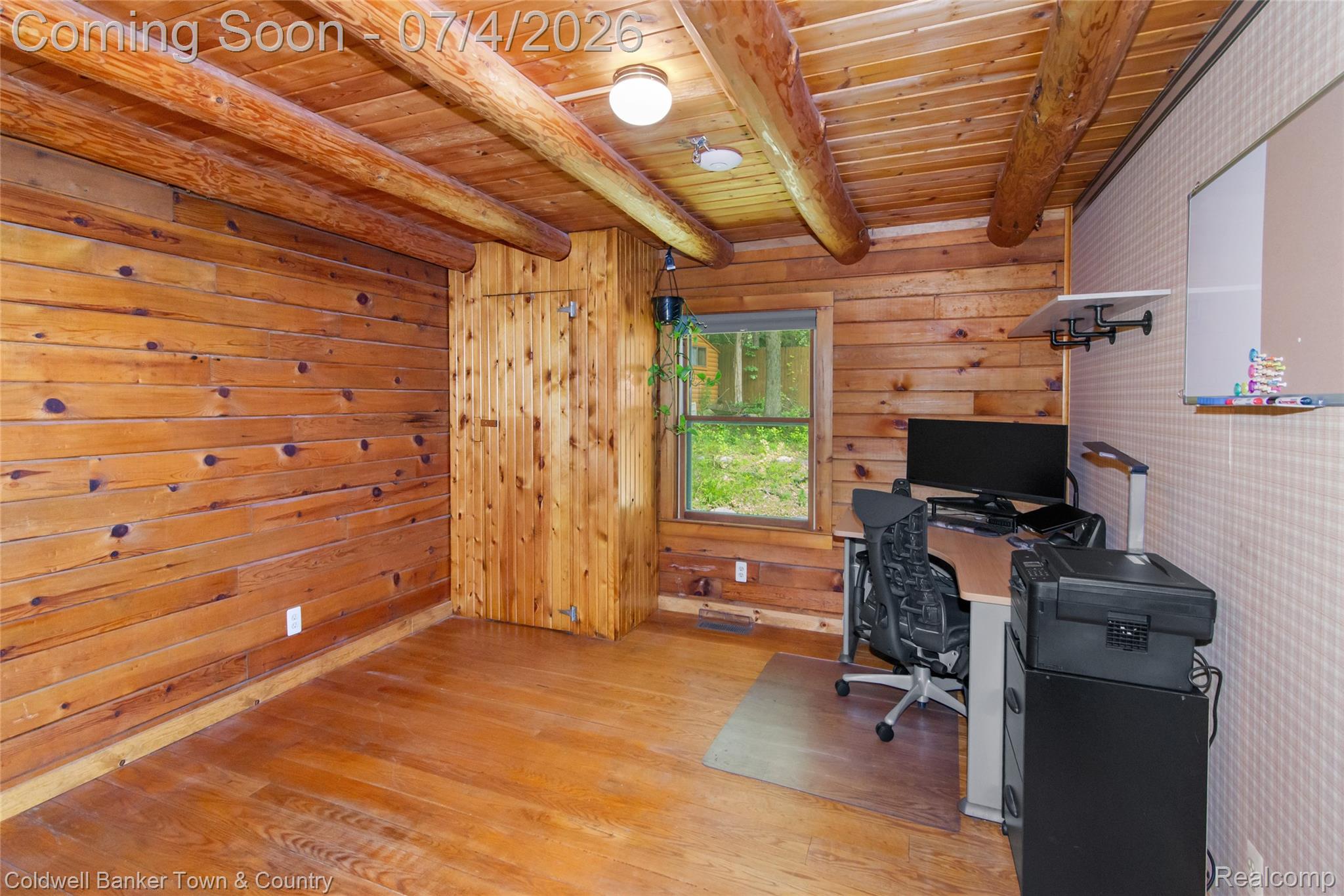 7335 Richardson Road Howell, MI 48843 - Photo 33 of 54 Wood-paneled room featuring a wood-finish floor, wood plank walls, and exposed log beams