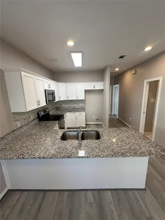 a kitchen with kitchen island granite countertop a sink a stove a counter space and cabinets