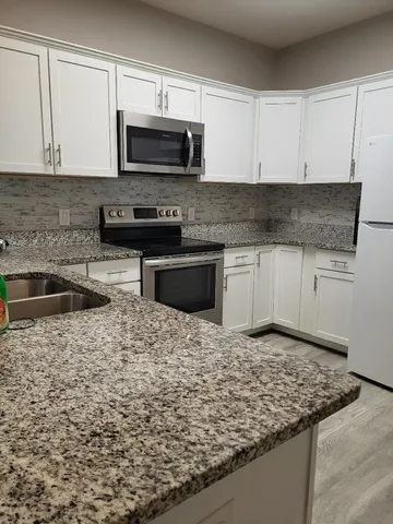 a kitchen with granite countertop a sink and a stove top oven