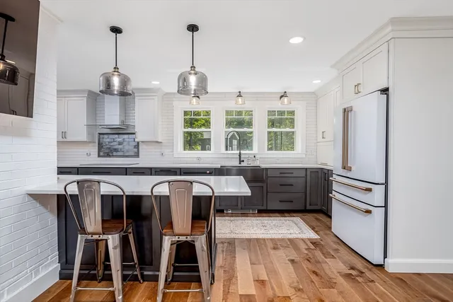 a kitchen with stainless steel appliances kitchen island granite countertop a refrigerator and a wooden floors