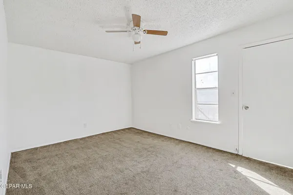 an empty room with closet and ceiling fan