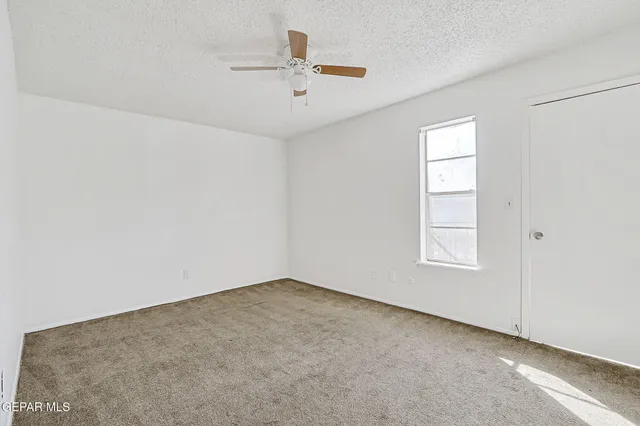 an empty room with closet and ceiling fan