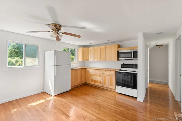 a kitchen with a refrigerator a stove top oven a window and a ceiling fan