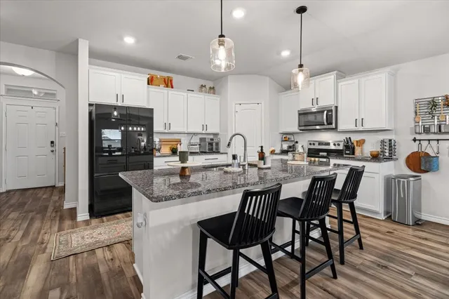 a kitchen with stainless steel appliances granite countertop a stove a refrigerator a kitchen island a sink and a refrigerator