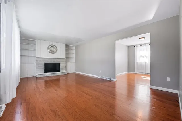 a view of empty room with wooden floor and fireplace