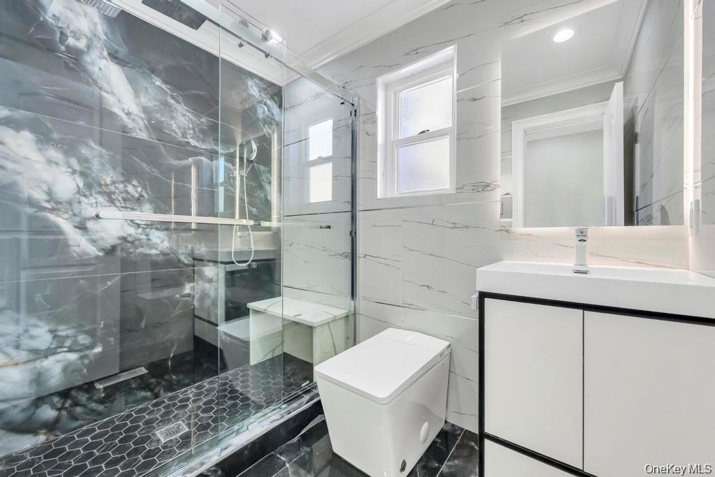 41 Perry Street Hempstead, NY 11550 - Photo 11 of 36 Bathroom featuring vanity, tile walls, a marble finish shower, ornamental molding, and stone wall