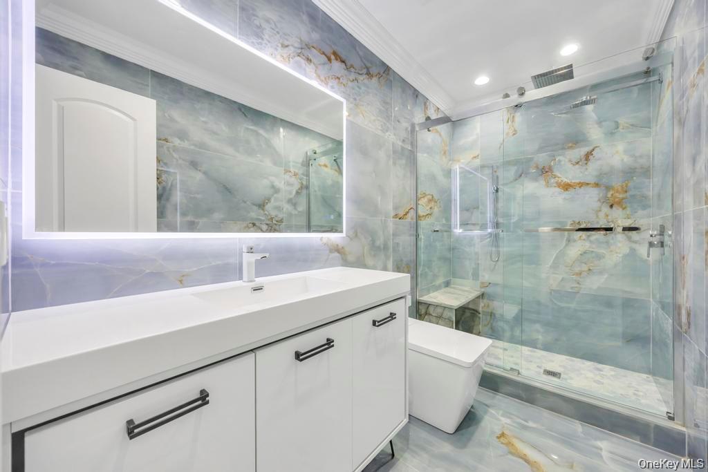 41 Perry Street Hempstead, NY 11550 - Photo 18 of 36 Full bath with tile walls, vanity, crown molding, a marble finish shower, and light marble finish flooring
