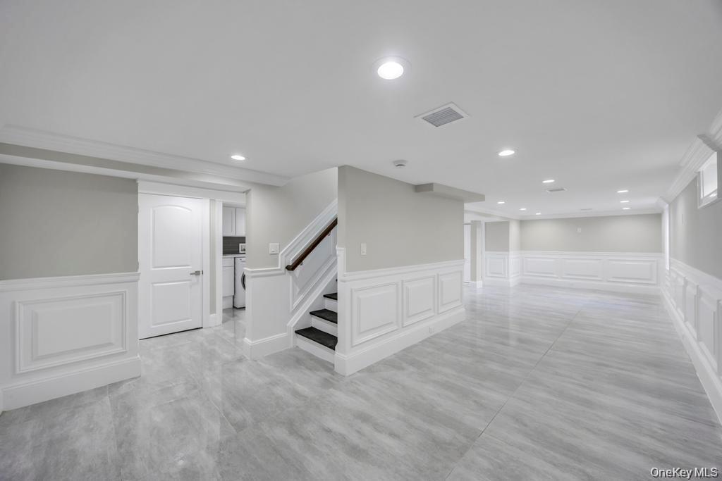 41 Perry Street Hempstead, NY 11550 - Photo 28 of 36 Finished below grade area featuring a decorative wall, wainscoting, recessed lighting, and stairs