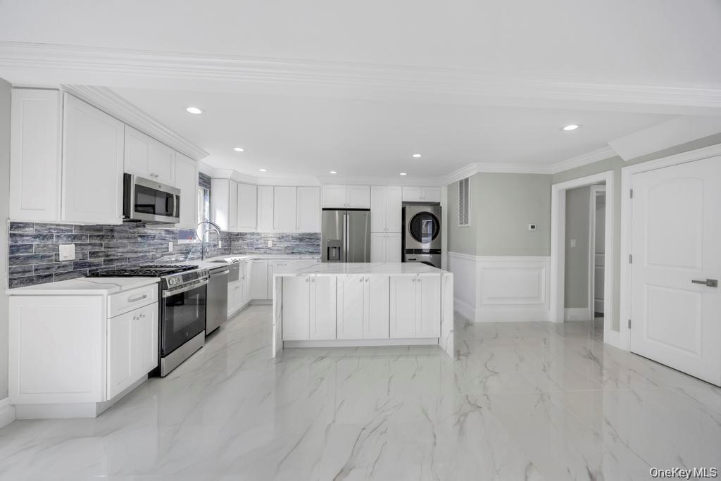 41 Perry Street Hempstead, NY 11550 - Photo 6 of 36 Kitchen with light marble finish floors, a wainscoted wall, appliances with stainless steel finishes, a center island, and white cabinetry