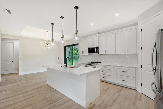 a large kitchen with stainless steel appliances granite countertop a sink a oven a stove and a wooden floors