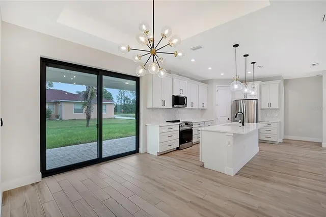 a large kitchen with white cabinets and stainless steel appliances
