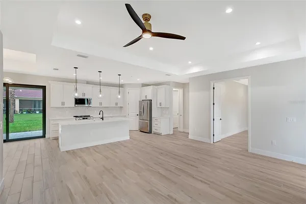 a large kitchen with kitchen island a stove a sink dishwasher and a refrigerator with wooden floor