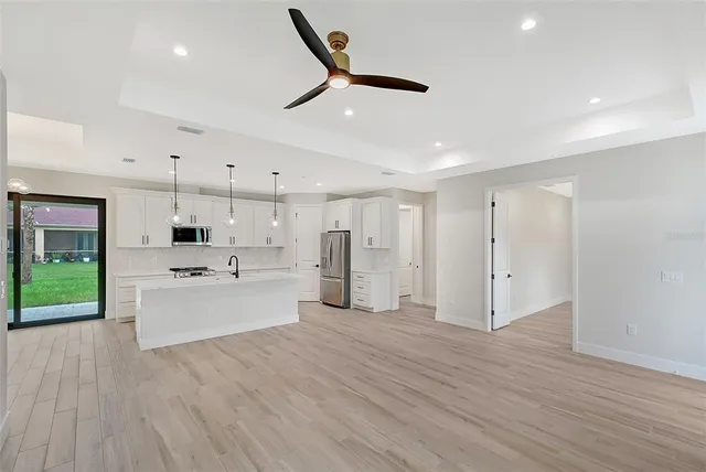 a large kitchen with kitchen island a stove a sink dishwasher and a refrigerator with wooden floor