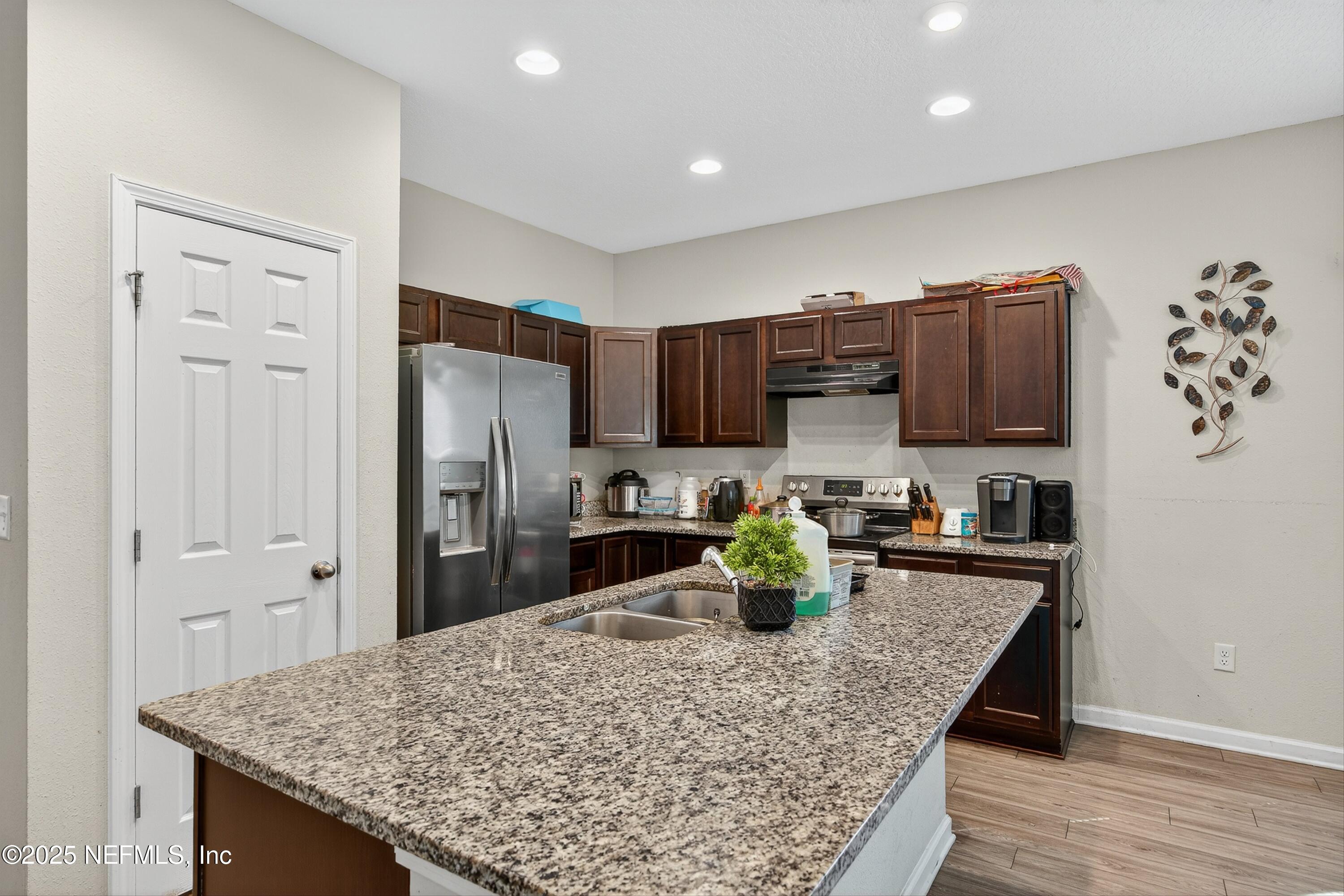 756 Talking Tree Drive Jacksonville, FL 32205 - Photo 14 of 26 a kitchen with stainless steel appliances granite countertop a refrigerator a stove a sink a microwave and wooden cabinets