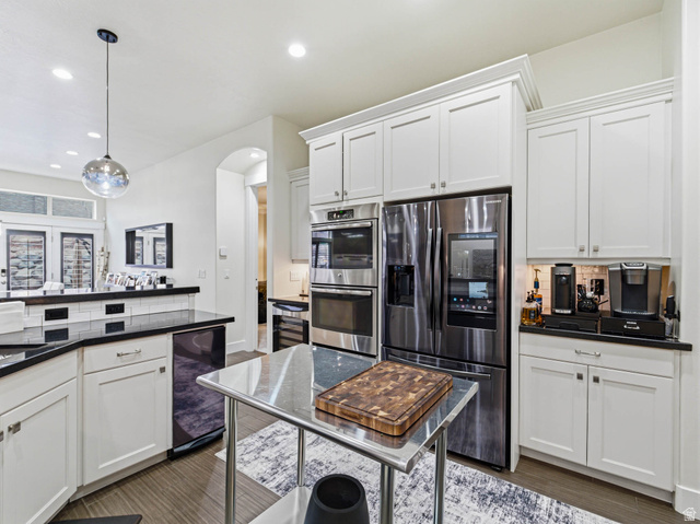 1154 Sunset Dunes Way Draper, UT 84020 - Photo 18 of 50 Kitchen featuring stainless steel appliances, white cabinetry, decorative light fixtures, arched walkways, and wine cooler