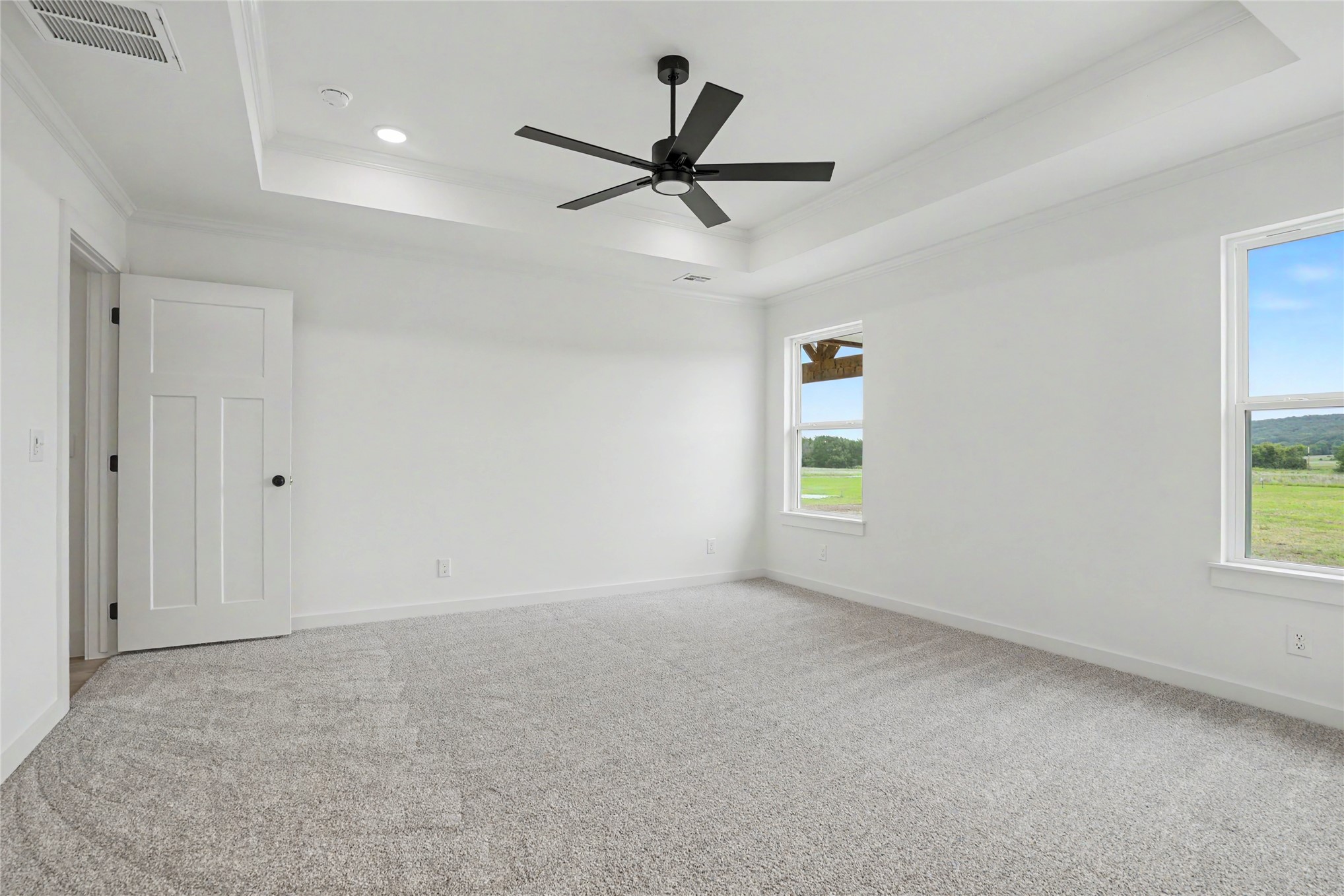 1445 South 4260th Road Chelsea, OK 74016 - Photo 17 of 33 Spacious room featuring a tray ceiling with recessed lighting and a ceiling fan, plush grey carpeting, and multiple windows offering expansive exterior views