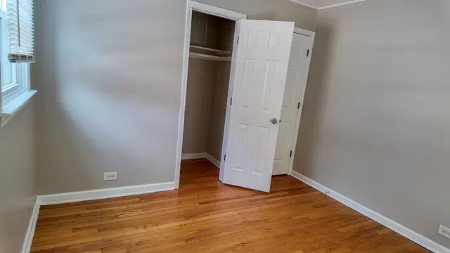 an empty room with wooden floor and entrance