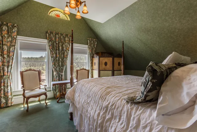 a bedroom with a bed a chair and a large window