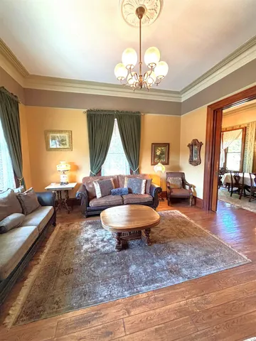 a living room with furniture a chandelier and a dining table