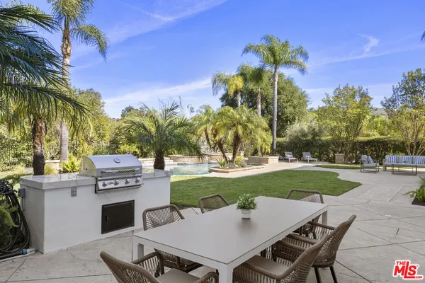 a view of a patio with table and chairs plants and palm trees