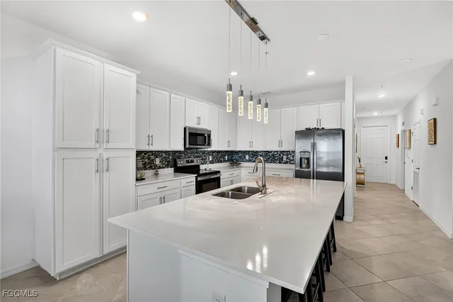 a kitchen with stainless steel appliances kitchen island granite countertop a refrigerator sink and white cabinets
