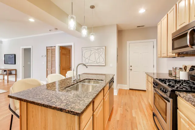 a kitchen with stainless steel appliances granite countertop a sink dishwasher stove and refrigerator with wooden floor