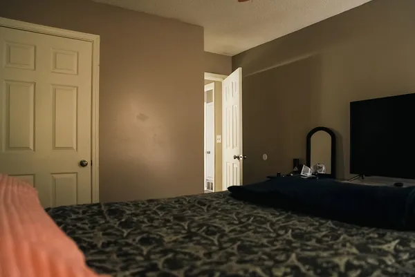 a bedroom with a bed and a flat tv screen on dresser