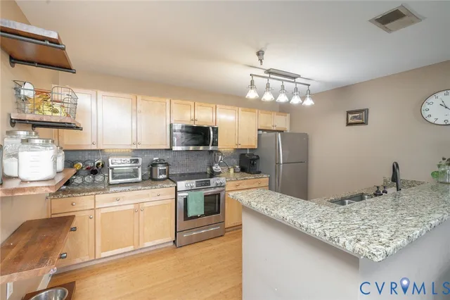 a kitchen with stainless steel appliances granite countertop a sink stove and refrigerator