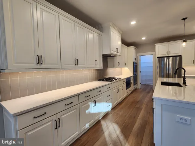 a large kitchen with stainless steel appliances granite countertop a sink a stove and a refrigerator