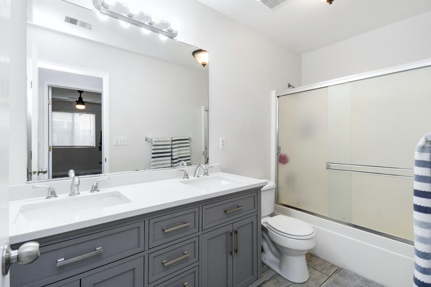 1435 Summerwind Drive Lemoore, CA 93245 - Photo 19 of 32 a bathroom with a toilet a sink and a mirror