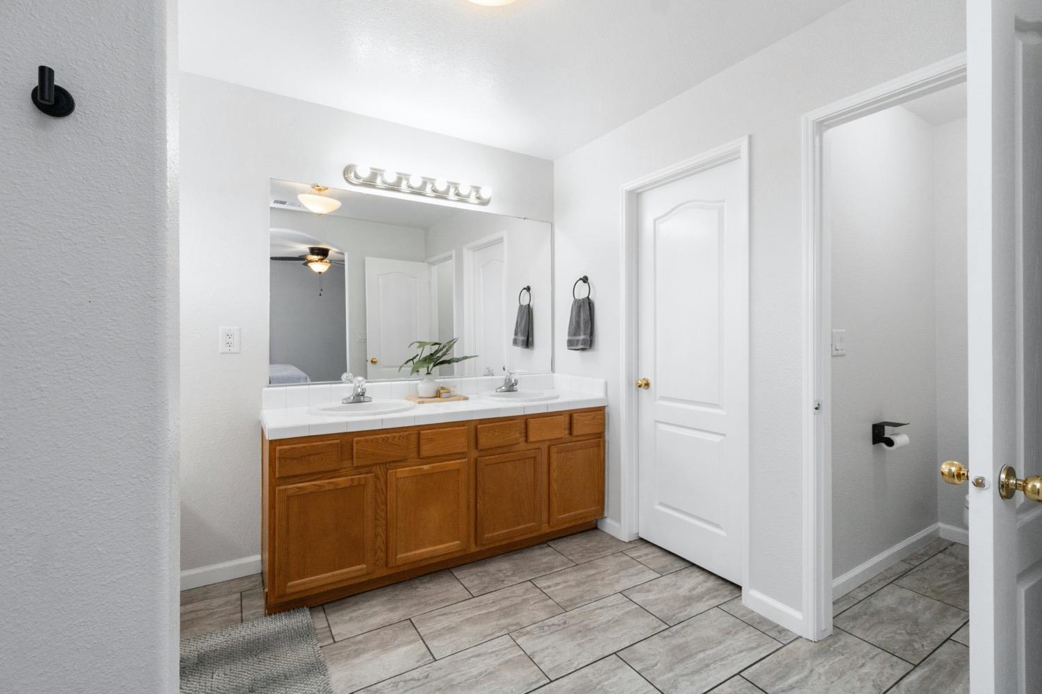 1435 Summerwind Drive Lemoore, CA 93245 - Photo 23 of 32 a spacious bathroom with a double vanity sink a mirror and a bathtub