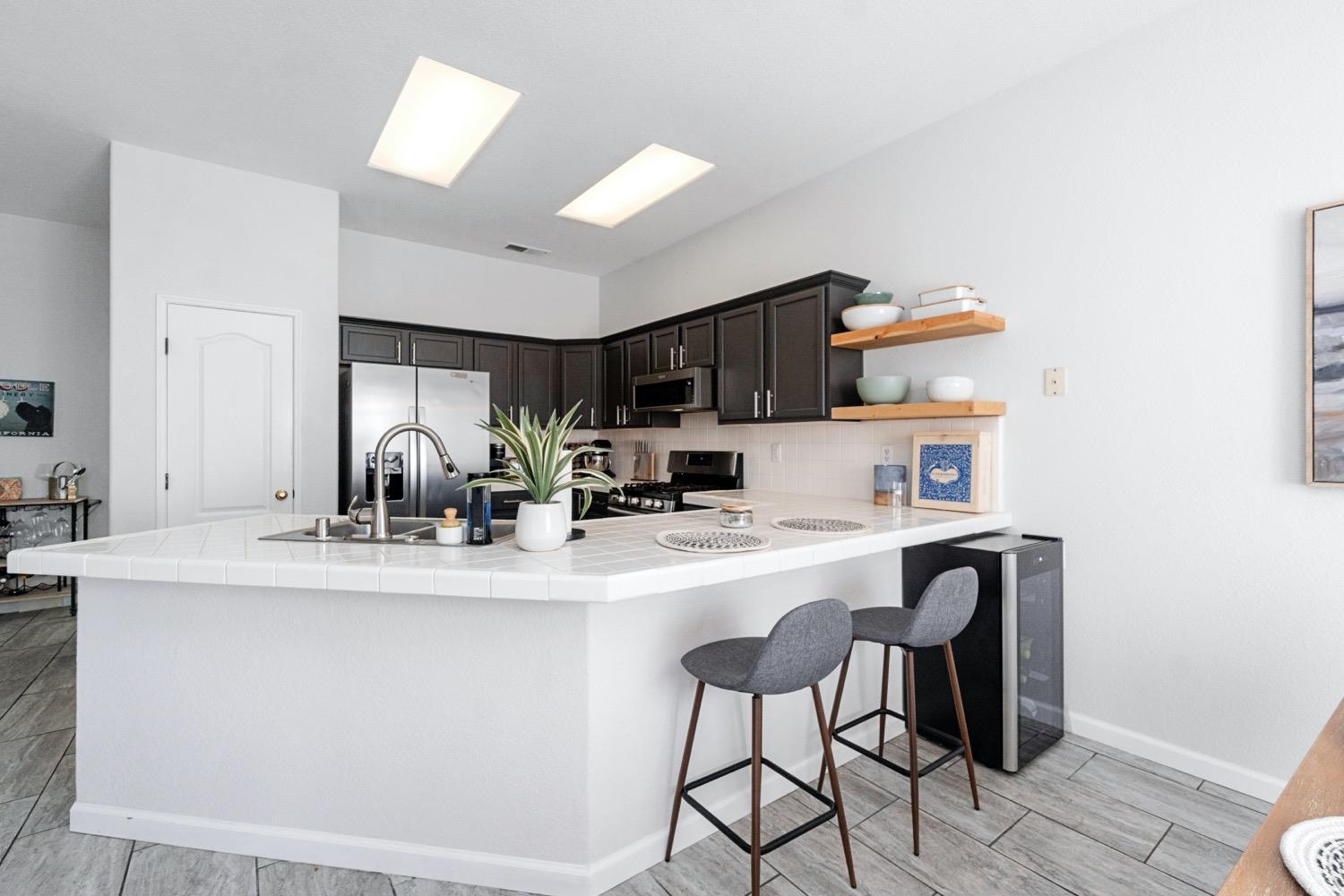 1435 Summerwind Drive Lemoore, CA 93245 - Photo 8 of 32 a kitchen with kitchen island a stove a table and chairs in it