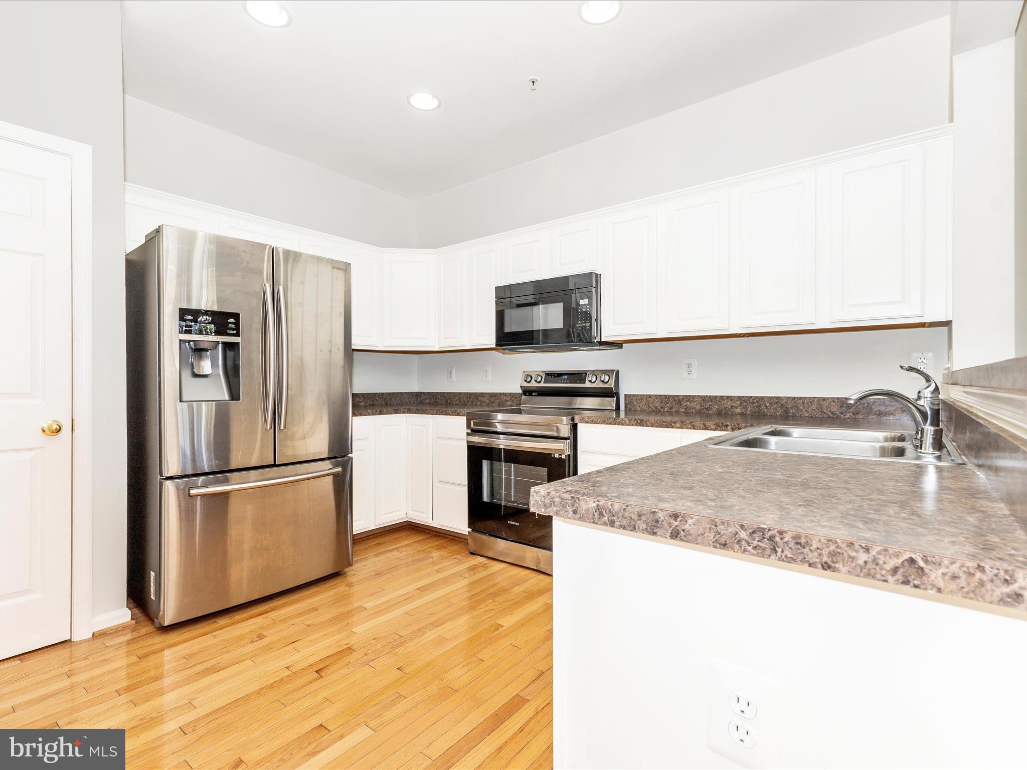 7096 Water Oak Road, Unit 121 Elkridge, MD 21075 - Photo 16 of 46 a kitchen with stainless steel appliances granite countertop a refrigerator a stove and a sink with wooden floor