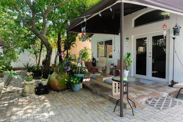 a view of a patio with table and chairs potted plants and floor to ceiling window